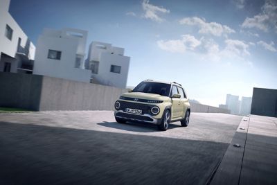 Nowy, elektryczny Hyundai INSTER jadący miejską ulicą.