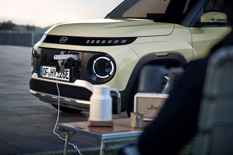 Hyundai INSTER plugged in to charge at a public charging station in an urban plaza.