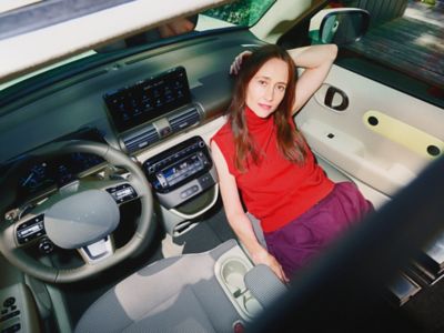 A woman reclining on the folded down front seat of the new Hyundai INSTER.