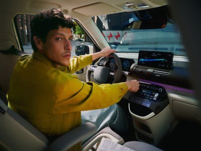 Un hombre sentado en el asiento del conductor del nuevo coche eléctrico compacto Hyundai INSTER.