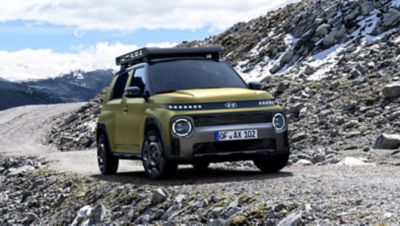 De Hyundai INSTER Cross van voren gezien op een rotsachtige weg in de bergen.