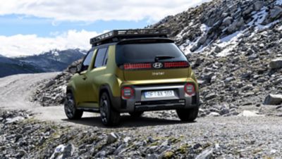 Hyundai INSTER Cross vue de l'arrière sur une route rocailleuse en montagne.