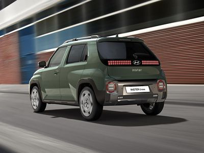 The rear view of Hyundai INSTER Cross trim driving on the street.