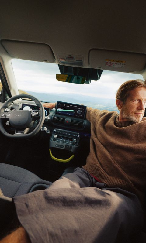 A man reclining on the folded down front seat of the new Hyundai INSTER.