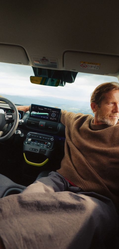 A man reclining on the folded down front seat of the new Hyundai INSTER Cross.