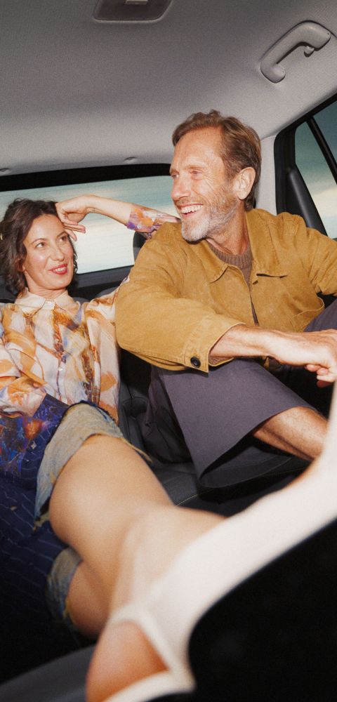 A man and a woman with her feet up laughing in the back seat of the Hyundai INSTER.