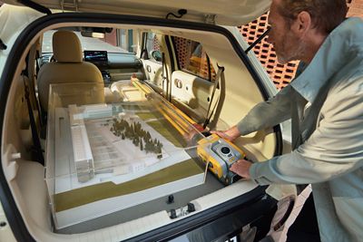Person loading an architectural model and surveying gear into the INSTER's rear cargo area.
