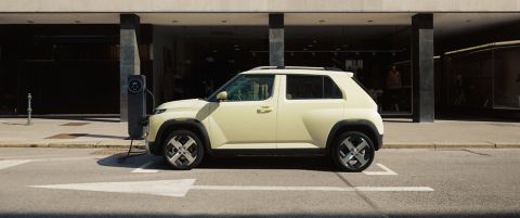  Side view of the Hyundai INSTER charging in front of a modern building.