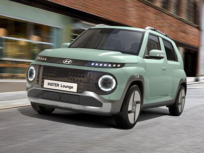 The Hyundai INSTER Lounge in Glow Mint exterior colour driving on a city street.