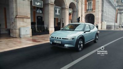 IONIQ 3  v modré barvě jedoucí ulicí.