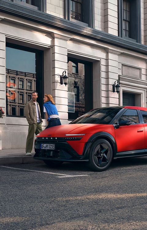 Red Hyundai IONIQ 3 shown from front three‑quarter angle on an urban street.