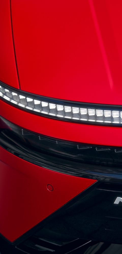 Red Hyundai IONIQ 3 front detail showing slim LED light strip and N Line badge on sculpted body.