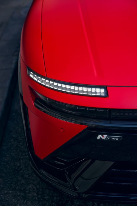 Red Hyundai IONIQ 3 front detail showing slim LED light strip and N Line badge on sculpted body.