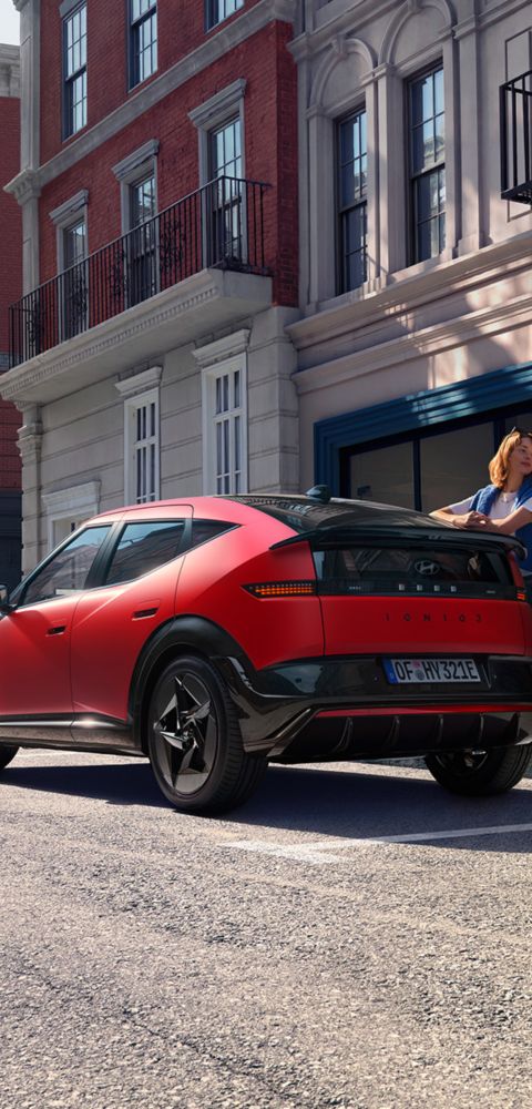 Red Hyundai IONIQ 3 shown from rear three‑quarter angle on an urban street.
