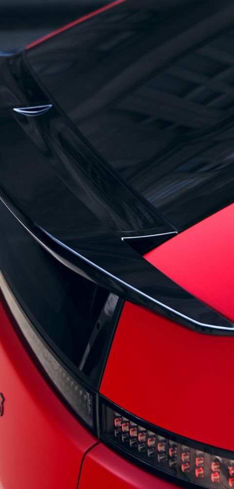 Red Hyundai IONIQ 3 rear detail with black roof spoiler and pixel-style LED taillight design.