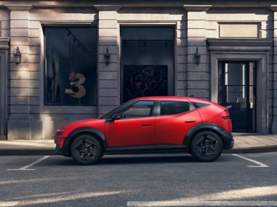 En rød IONIQ 3 står parkert i et bymiljø. Foto.