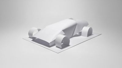 Paper model shaped like a simplified car placed on a flat surface.