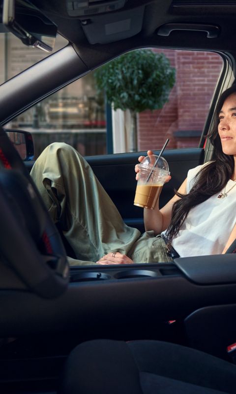 Interior view of a Hyundai IONIQ 3 showing a person seated in the front passenger seat, with the centre console and cup holders