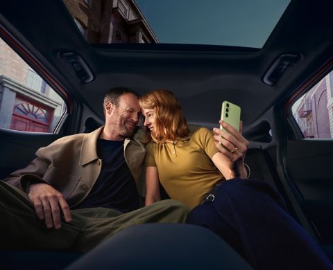 Interior of a Hyundai IONIQ 3 with black seats; two people relaxing in the rear seats.
