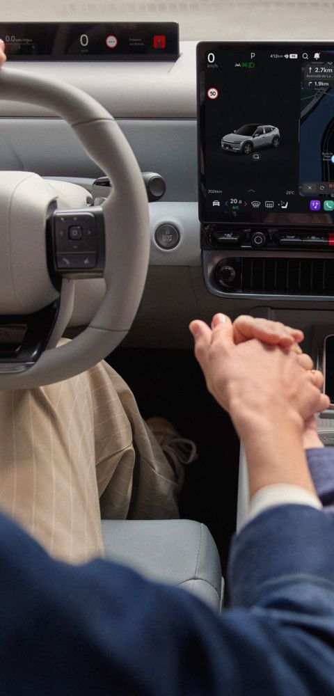 Close up of two people holding hands in front of the center touch screen of the Hyundai IONIQ 3.