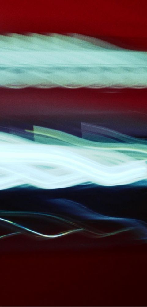 Hyundai IONIQ 3 light trails in white and blue against a red background.