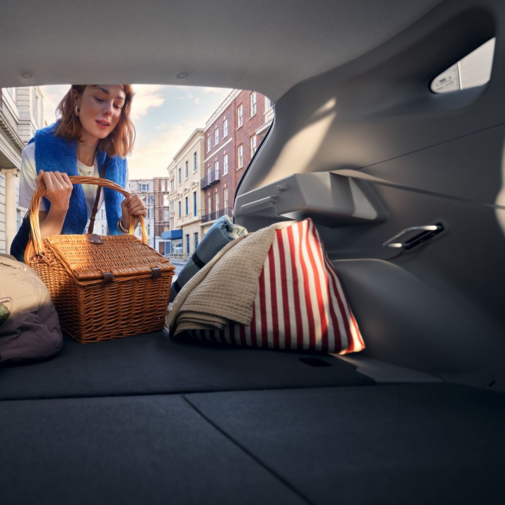 Žena ukládá piknikový koš do zavazadlového prostoru Hyundai IONIQ 3 se sklopenými zadními sedadly.