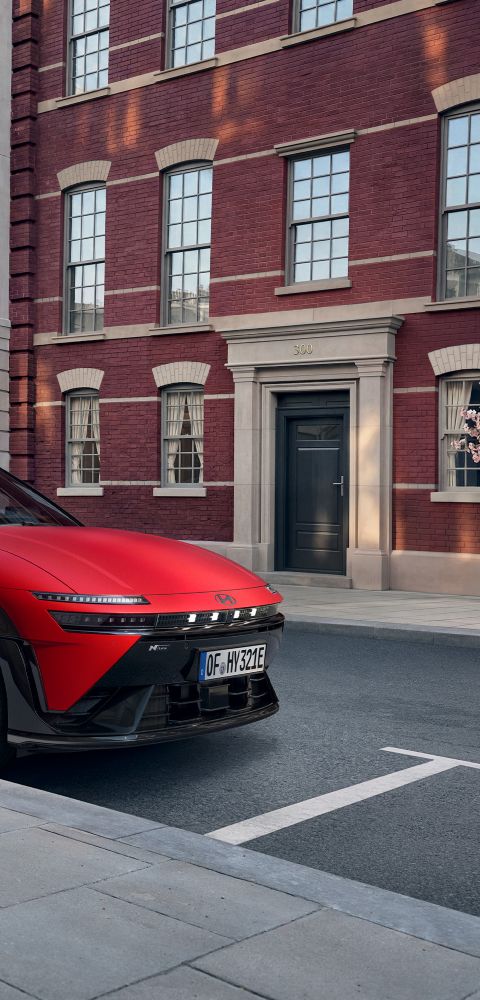 Red Hyundai IONIQ 3 N Line parked on a city street in front of attractive old buildings.