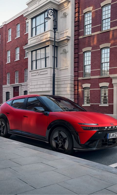 Red Hyundai IONIQ 3 N Line parked on a city street in front of attractive old buildings.