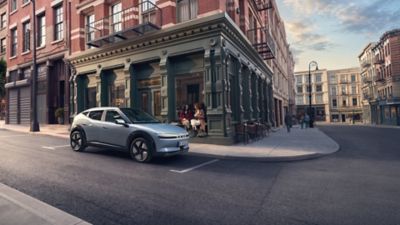 Hyundai IONIQ 3 EV parked on a city street with two woman sitting on a stoop next to it.