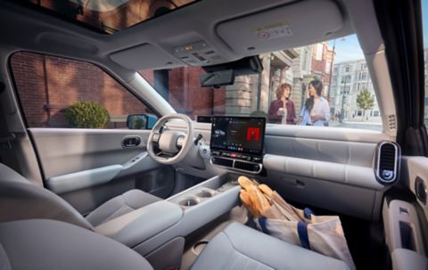 Interior of the Hyundai IONIQ 3 with a bag of baguettes on the front passenger side floor.