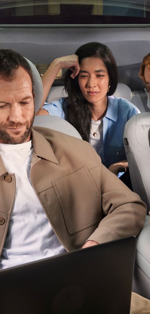 Three people sitting inside the Hyundai IONIQ 3, the man working on a laptop.