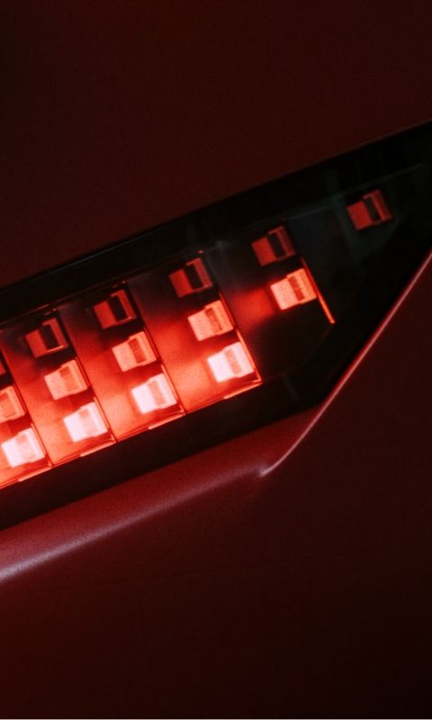 Red Hyundai IONIQ 3 rear light close-up showing illuminated pixel-style LEDs.