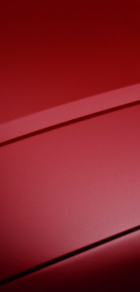 Red Hyundai IONIQ 3 sculpted body lines close-up on smooth exterior surface.