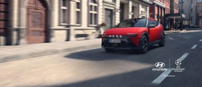Red Hyundai IONIQ 3 driving on a city street.