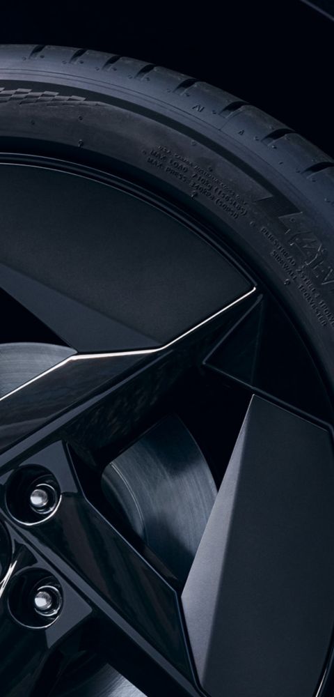 Wheel detail with black alloy rim featuring angular aero-inspired design.