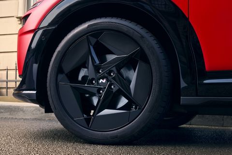 Wheel detail with black alloy rim featuring angular aero-inspired design.
