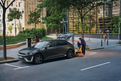 Hyundai IONIQ 5 EV parked on a sandy beach at sunset, the female driver leaning against the door.