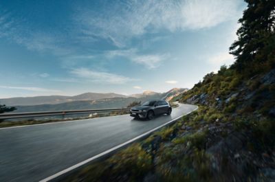 Ein IONIQ 5 N Line fährt auf einer Landstraße mit malerischem Bergpanorama im Hintergrund