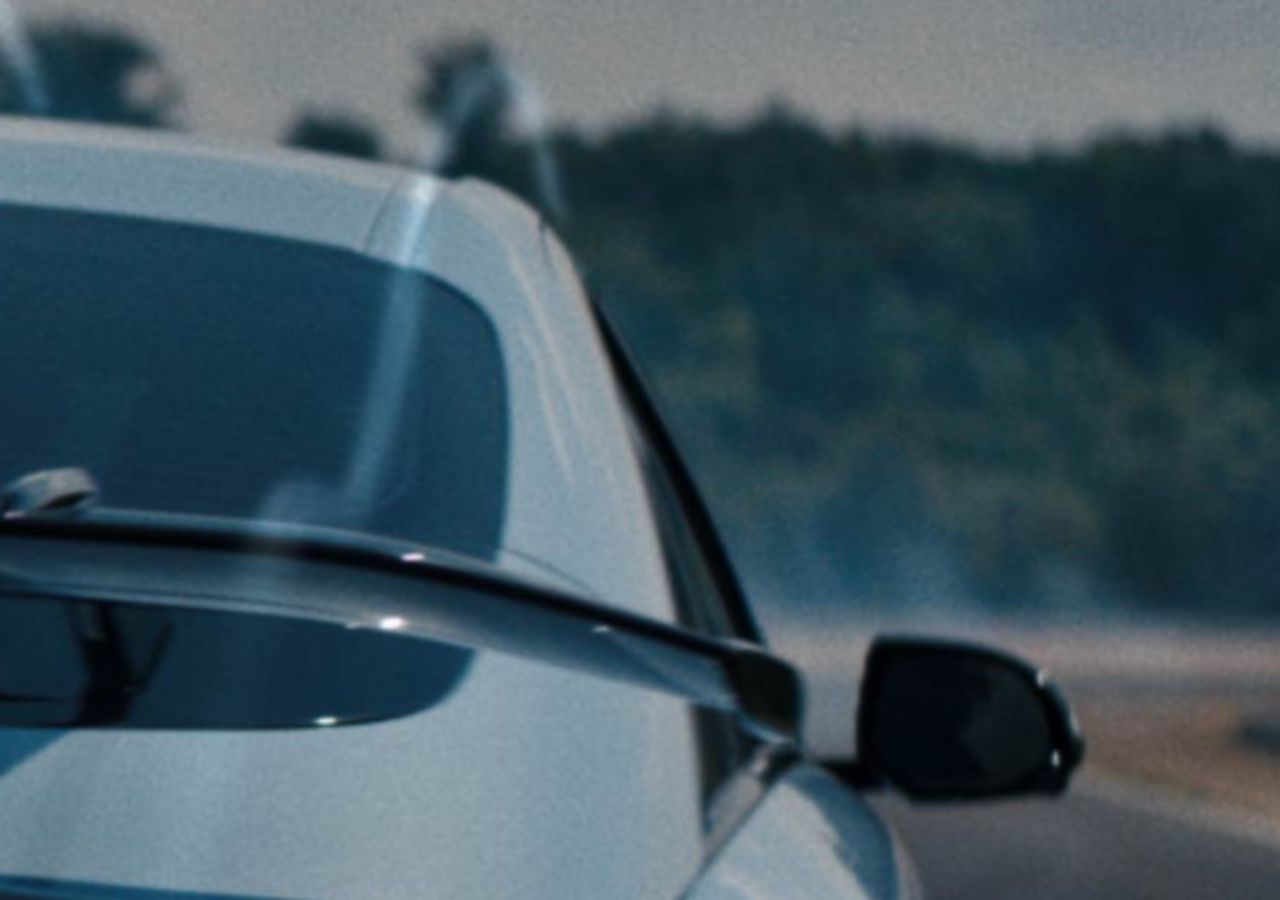 Rear view of a Hyundai IONIQ 6 N on a track, showcasing dynamic aerodynamics with smoke trailing behind.