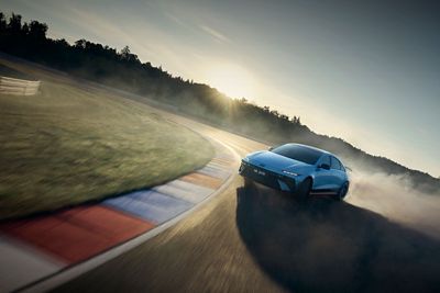 Der Hyundai IONIQ 6 N, das elektrische Performance-Fahrzeug, rast über eine sonnendurchflutete Rennstrecke unter klarem Himmel.