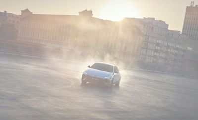 La berline électrique Hyundai IONIQ 6 N à haute performance effectuant des figures de drift dans les rues urbaines avec la silhouette de la ville en arrière-plan.
