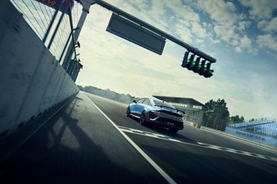 Widok z tyłu elektrycznego samochodu wyścigowego Hyundai IONIQ 6 N startującego z linii startu na torze wyścigowym podczas wyścigu z dużą prędkością