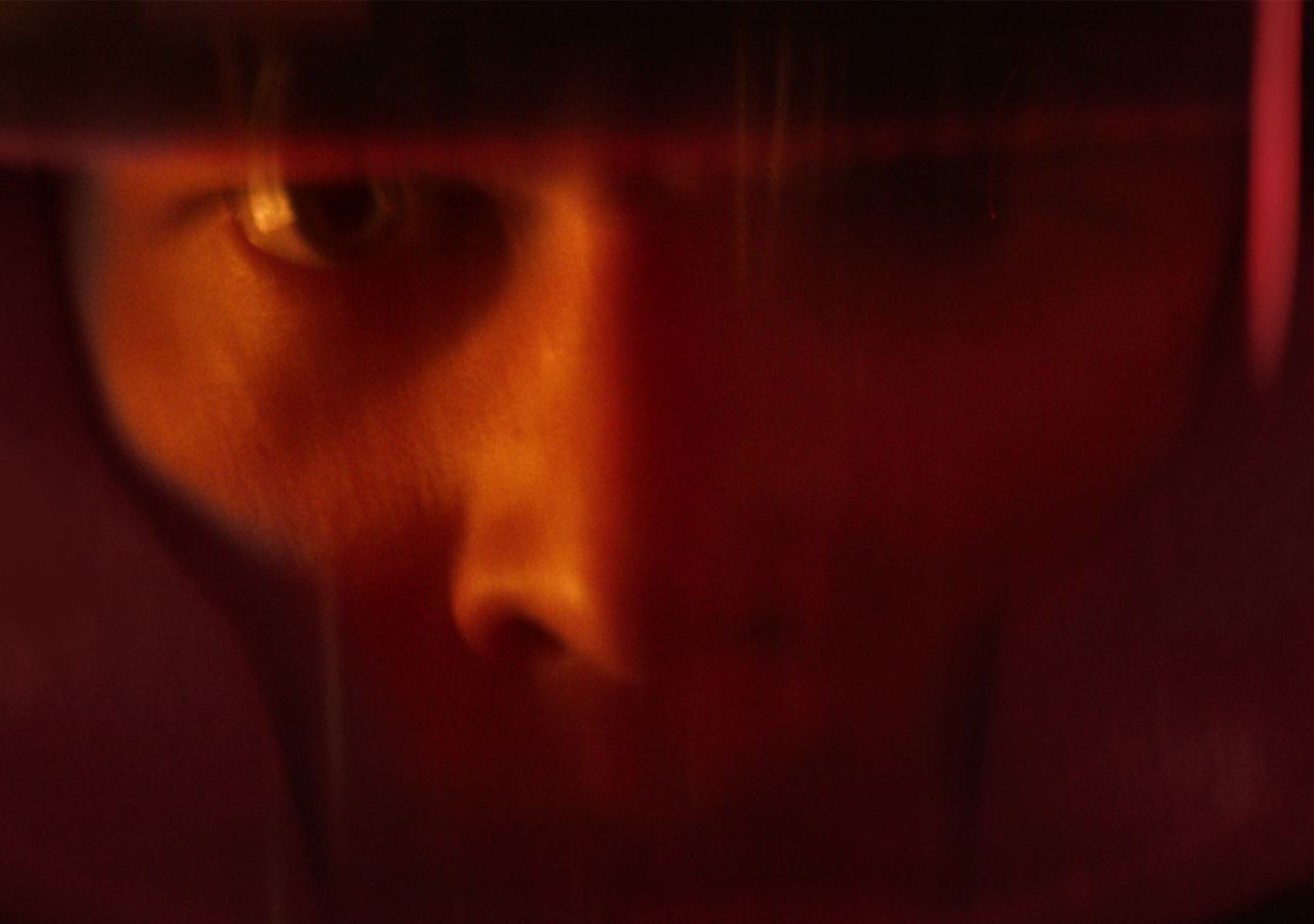 A close-up of a person's face wearing a reflective visor, revealing intense focus and determination.