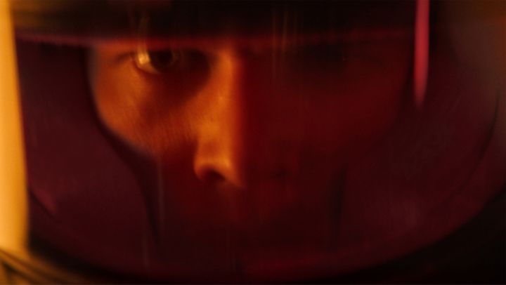A close-up of a person's face wearing a reflective visor, revealing intense focus and determination.