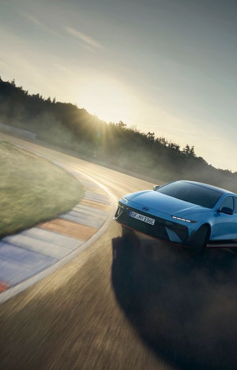 Hyundai IONIQ 6 N drifting on a racetrack, kicking up dust in a dynamic position during a drive.
