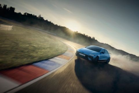 Hyundai IONIQ 6 N drifting on a racetrack, kicking up dust in a dynamic position during a drive.