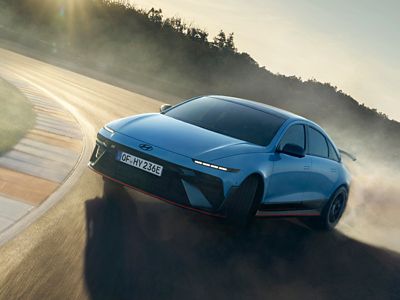 Hyundai IONIQ 6 N drifting on a racetrack, kicking up dust in a dynamic position during a drive.