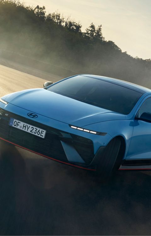 Ein Hyundai IONIQ 6 N wirbelt beim Durchfahren einer Rennstreckenkurve Staub auf. 