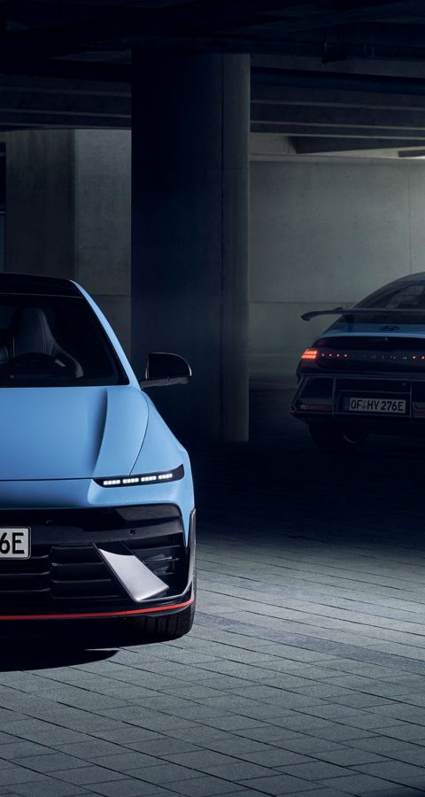 Two Hyundai IONIQ 6 N electric performance sedans in a dimly lit parking garage, front and rear view.