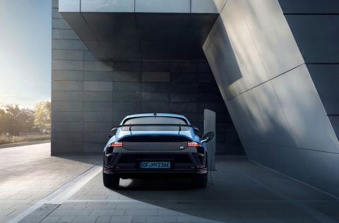 Rear view of a Hyundai IONIQ 6 N parked near a modern building with its driver-side door open.